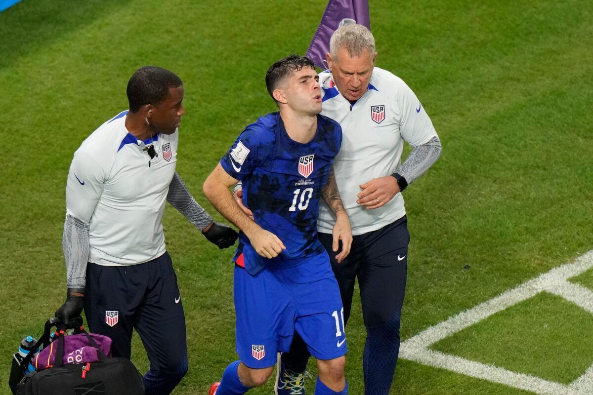Christian Pulisic of the United States is helped by team doctors after he scored his side's opening goal during the World Cup group B soccer match between Iran and the United States at the Al Thumama Stadium in Doha, Qatar, on Nov. 29, 2022. (Luca Bruno/AP Photo)