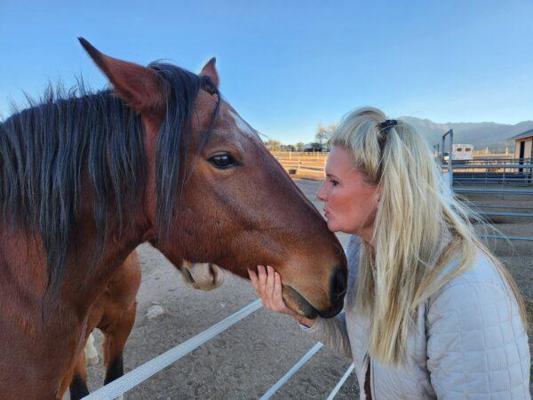 Simone Netherlands, president of the Salt River Wild Horse Management Group, comforts a rescued wild horse at the organization's animal sanctuary in Prescott, Ariz., on Nov. 30, 2022. (Allan Stein/The Epoch Times)