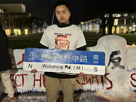 University of Pittsburgh senior Haoxuan Huang at a candlelight vigil to mourn Urumqi fire victims, on Dec. 2, 2022. He holds a sign for Shanghai's Wulumuqi Road. Signs for the road, which was named after Urumqi, site of the deadly Nov. 24 fire, were removed after they became a rallying point for protesters. Visible behind Huang is Chinese language vandalism of students' pro-freedom slogans. (Courtesy of Haoxuan Huang)