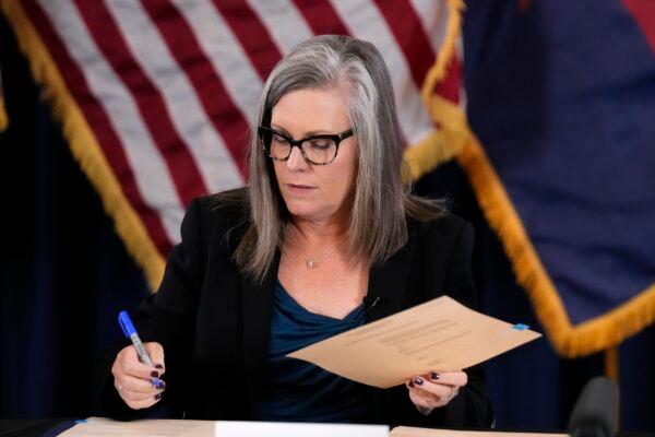 Katie Hobbs, the Democrat governor-elect and current secretary of state, signs the official certification for the Arizona general election canvass during a ceremony at the Arizona Capitol in Phoenix, Ariz., on Dec. 5, 2022. (Ross D. Franklin/AP Photo)