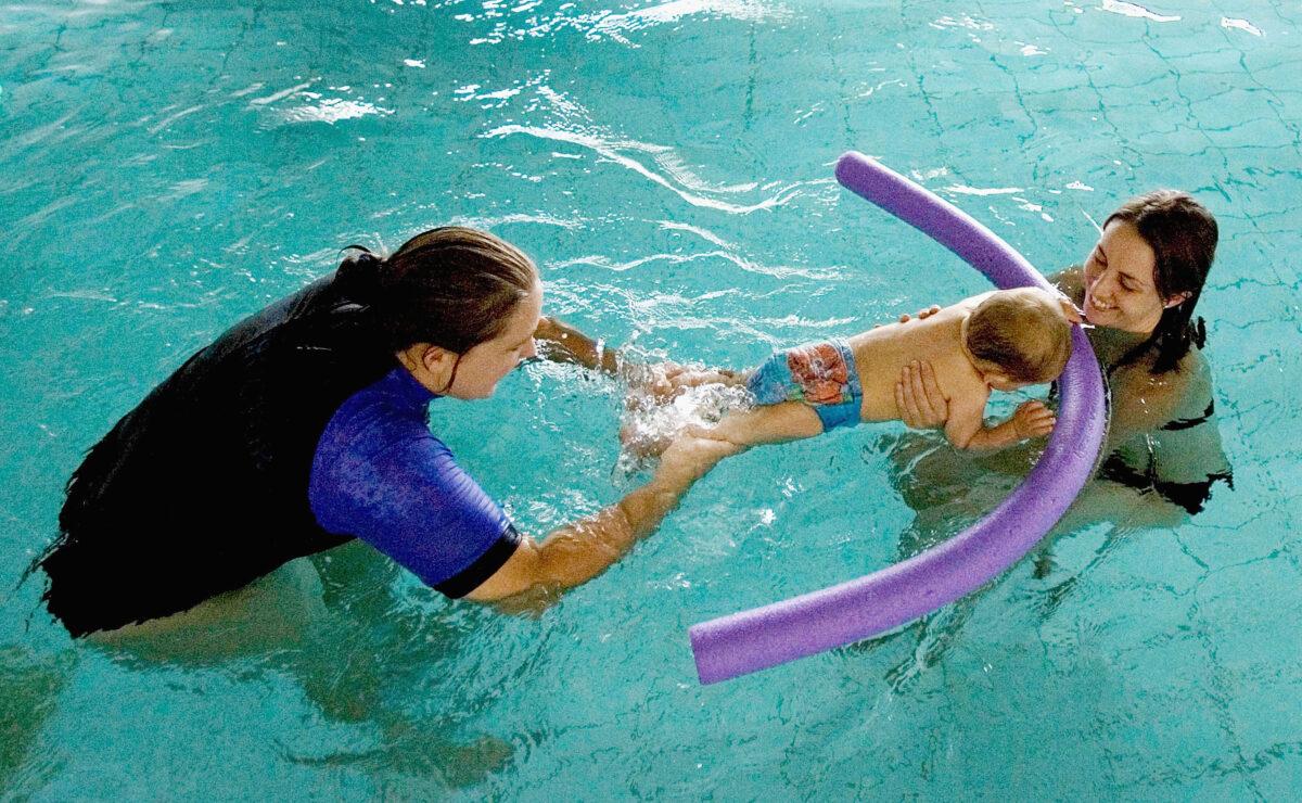 A toddler explores the water with his mother as an instructor at a swimming class in Sydney, Australia, on March 16, 2007. (Ian Waldie/Getty Images)