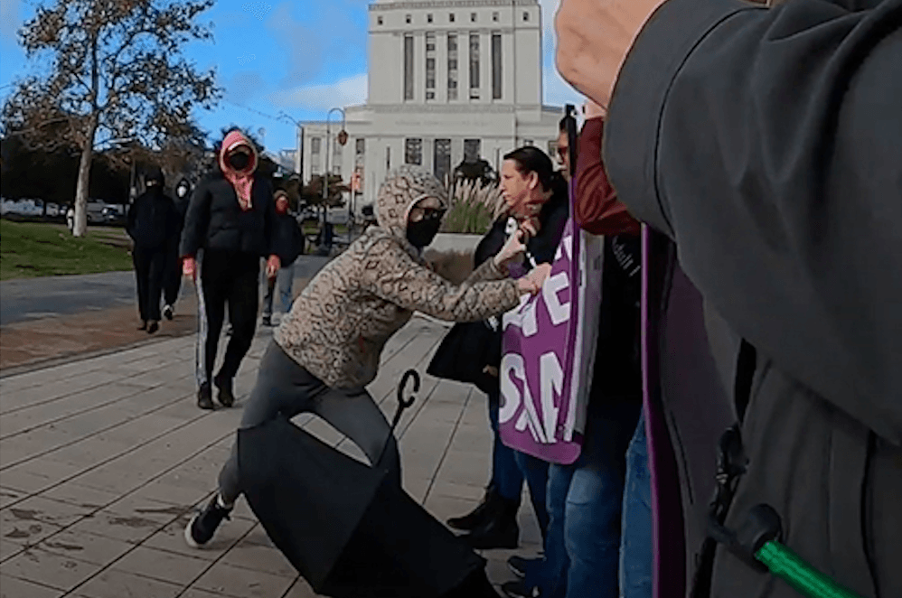 Women protesting the possible transfer of convicted killer Dana Rivers—a biological man who identifies as female—to a women’s prison are attacked outside of the Alameda County Superior Courthouse in Oakland, Calif., on Dec. 5, 2022. (Courtesy of Women's Declaration International, U.S.A.)