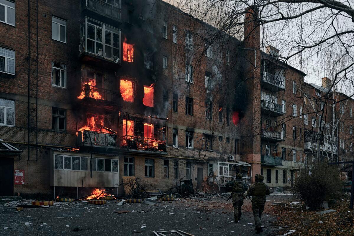 Ukrainian soldiers run to help people in an apartment building on fire after Russian shelling in Bakhmut, Donetsk region, Ukraine, on Dec. 7, 2022. (LIBKOS/AP Photo)