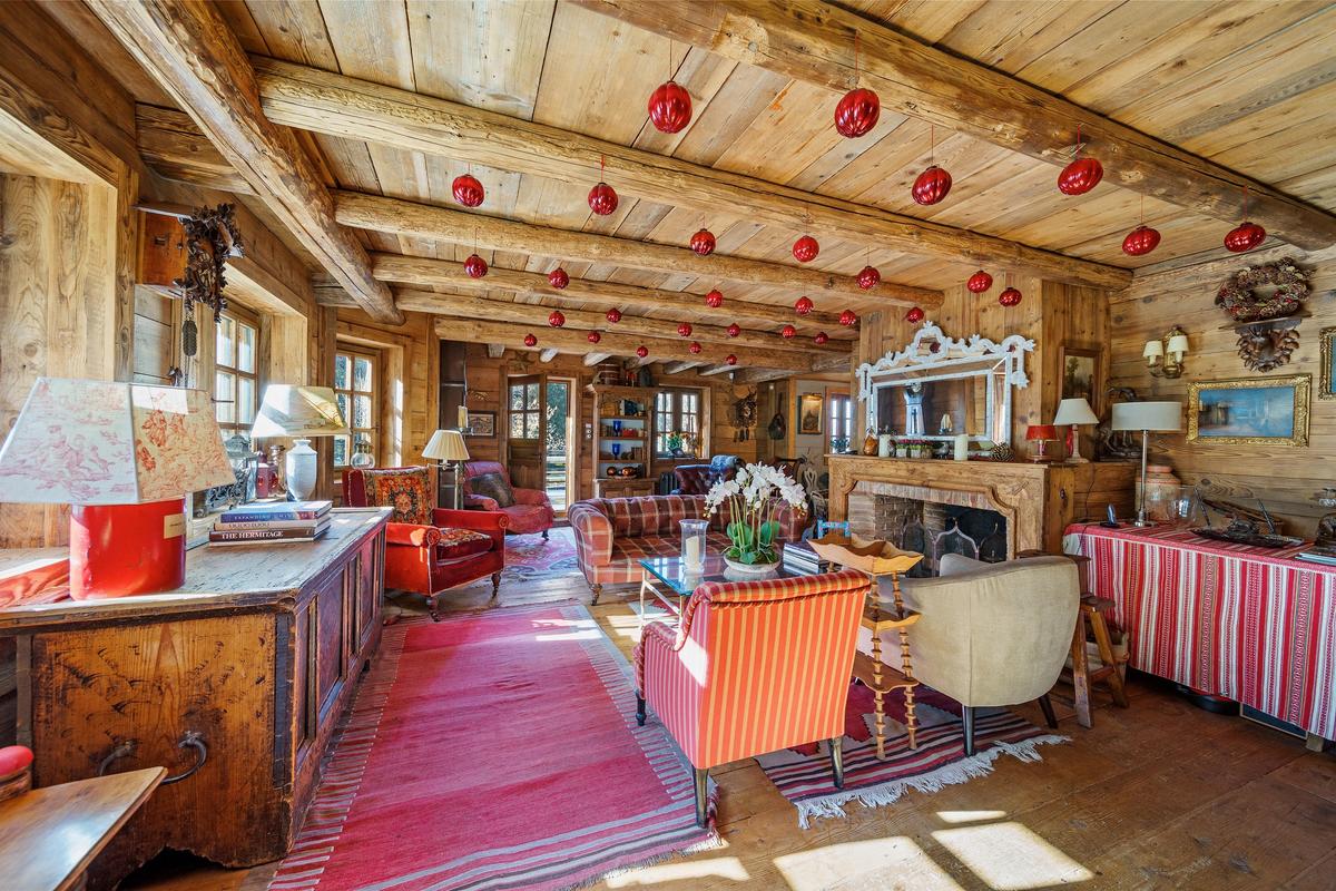 The chalet’s living room looks the main room of a world-class ski resort, with comfortable seating areas and a roaring fireplace accented by wood floors, wood-paneled walls and an exposed beam ceiling. (Courtesy of Sotheby’s Concierge Auctions)