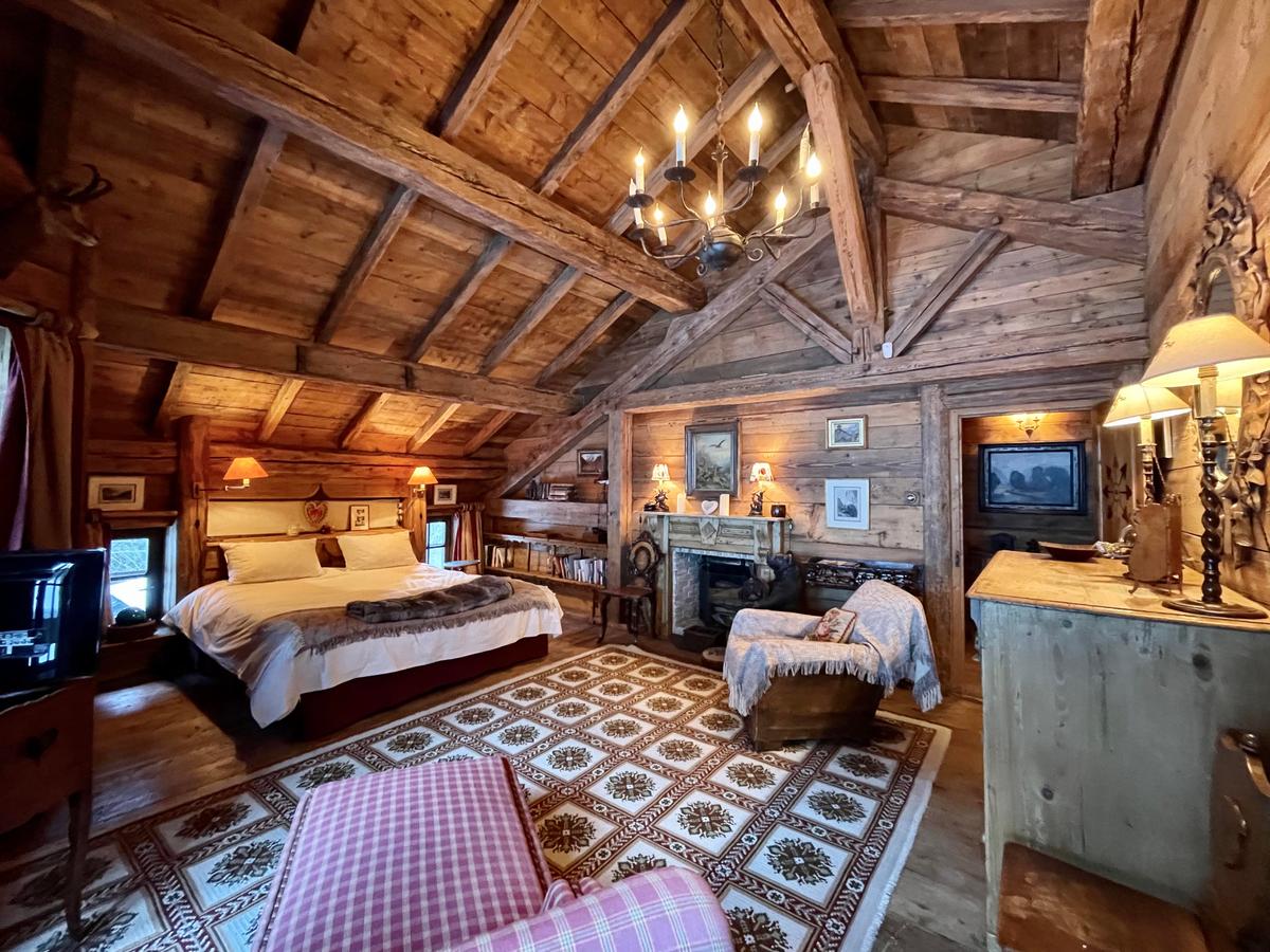 The master bedroom is a perfect example of ski lodge chic, featuring a fireplace and gleaming chandelier, accenting the wood floors, walls and exposed-beam ceiling. (Courtesy of Sotheby’s Concierge Auctions)