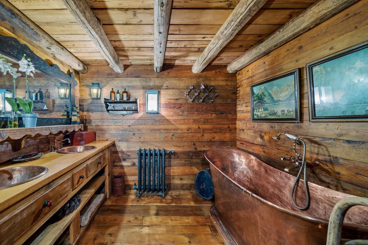 This bathroom with its vintage copper tub and sinks, radiator heater, and wood floors, walls, and ceiling is the ideal place to enjoy a long, hot bath after a day of skiing. (Courtesy of Sotheby’s Concierge Auctions)