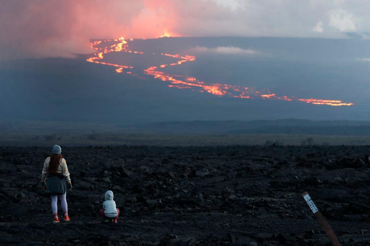 Spectators watch the lava flow down the mountain from the Mauna Loa eruption near Hilo, Hawaii, on Nov. 29, 2022. (Marco Garcia/AP Photo)