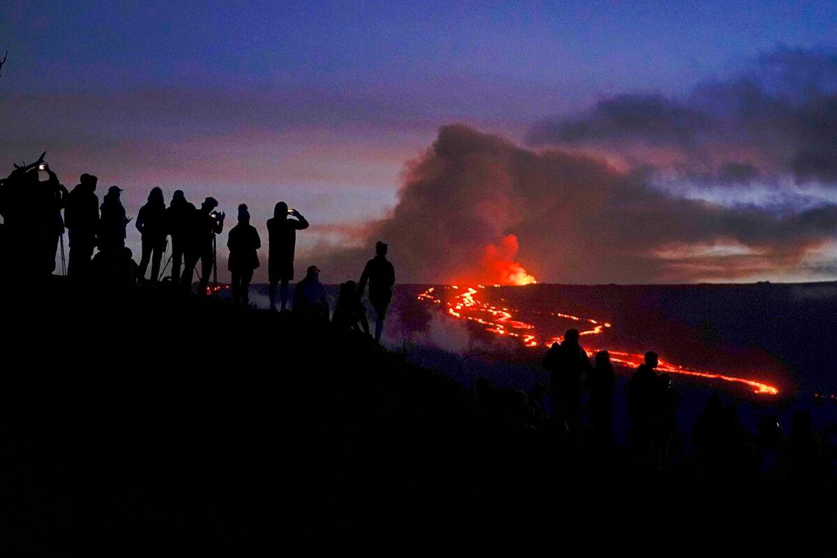 People watch and record images of lava from the Mauna Loa volcano near Hilo, Hawaii, on Dec. 1, 2022. (Gregory Bull/AP Photo)