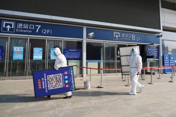 Staff members removing posters for a COVID-19 health code used upon entering the railway station in Xining, Qinghai Province, China, on Dec. 8, 2022. ( -/CNS/AFP via Getty Images)