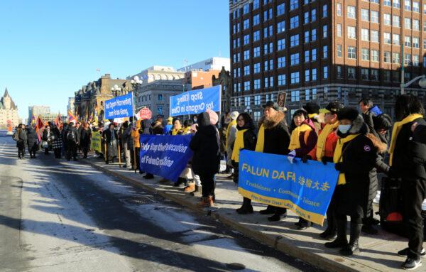 Adherents of the spiritual practice Falun Gong hold banners at a rally in front of the West Block on Parliament Hill in support of a bill to combat forced organ harvesting, in Ottawa on Dec. 14. (Jian Ren/The Epoch Times)
