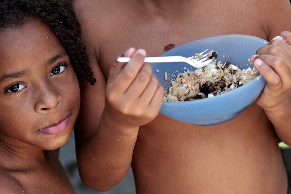 Thawanny Silva de Souza (L), 6, and Rafael Silva de Souza (R), 9, eat a lunch of rice, beans, and egg in their family's house, in the Arco Iris favela in Recife, Brazil, on Sept. 15, 2022. (Ueslei Marcelino/Reuters)