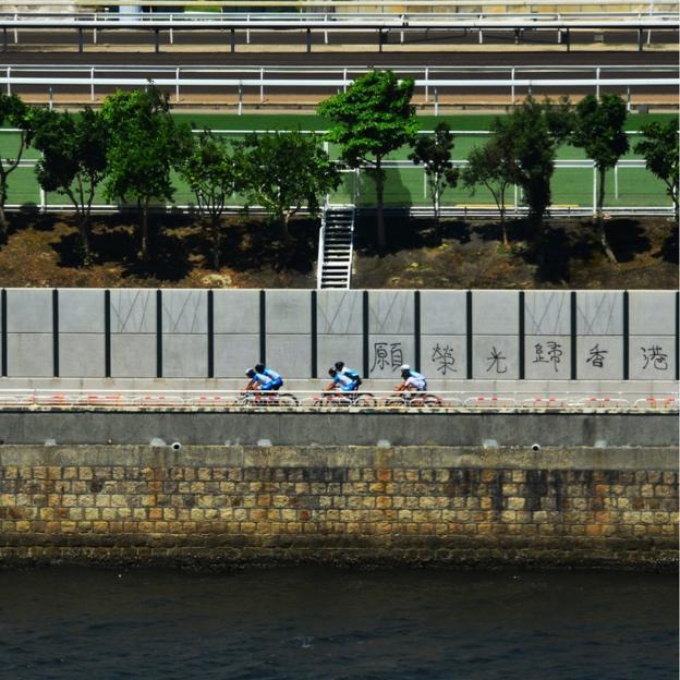 In 2019, in Sha Tin, Hong Kong, several cyclists rode past the Shing Mun River with "Glory to Hong Kong" spray-painted on the fence behind them, Dec. 2019.  (Courtesy of Cheung Chan-fai)