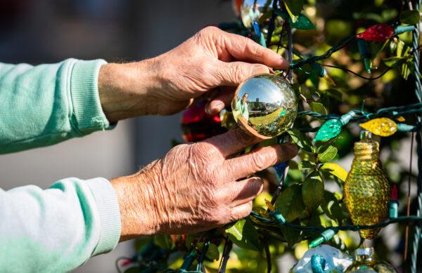 James "Jim" Val adjusts items on his outdoor Christmas tree at his home in Arcadia, Calif., on Dec. 9, 2022. (John Fredricks/The Epoch Times)