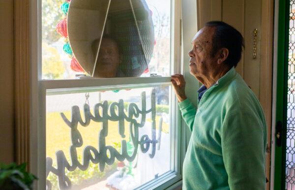 James "Jim" Val looks out the window of his home in Arcadia, Calif., on Dec. 9, 2022. (John Fredricks/The Epoch Times)