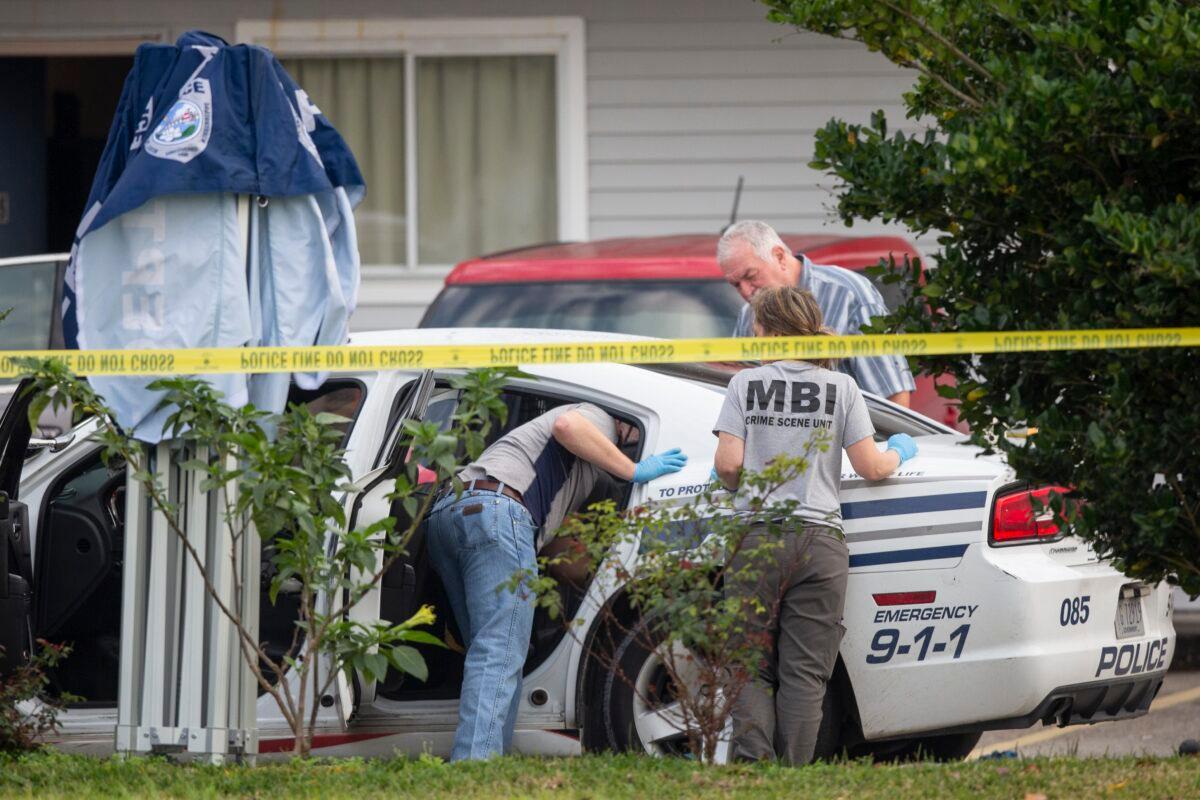 Mississippi Bureau of of Investigations investigators inspected a police vehicle on the scene of the murder of two police officers outside a Motel 6 in Bay St. Louis, Miss., on Dec. 13, 2022. (Hannah Ruhoff/The Sun Herald via AP)