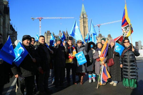 Conservative MP Garnett Genuis (C) poses with Uyghur and Tibetan protesters as they rally in front of the West Block on Parliament Hill in support of a bill to combat forced organ harvesting, in Ottawa on Dec. 14. (Jian Ren/The Epoch Times)