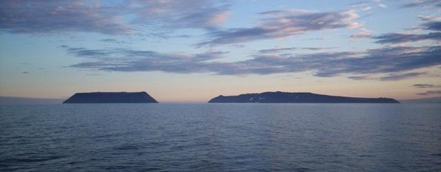 Little Diomede Island (left) and Big Diomede Island in the Bering Sea. (Dave Cohoe/<a href="https://commons.wikimedia.org/wiki/File:Diomede_Islands_Bering_Sea_Jul_2006.jpg">CC BY 3.0</a>)
