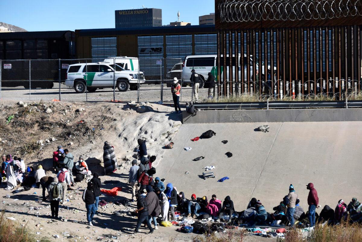Illegal immigrants wait to cross the U.S.-Mexico border from Ciudad Juárez, next to U.S. Border Patrol vehicles in El Paso, Texas, Wednesday, Dec. 14, 2022. (AP Photo/Christian Chavez)