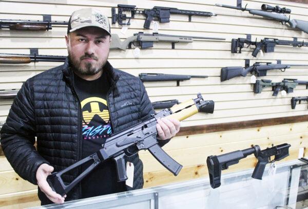 Justin Barrett, owner of Barrett Outdoors in Durant, Oklahoma, displays an AK pistol with a pistol stabilizing brace. On the counter next to him is a similar brace for an AR15 pistol.