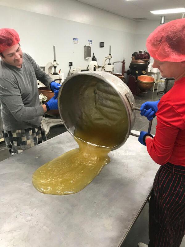 The freshly cooked cane batter is poured onto a heated table, then folded, kneaded, and flipped. The batter is then shaped into a log and decorated with handmade stripes. (Courtesy of Greg Clark)