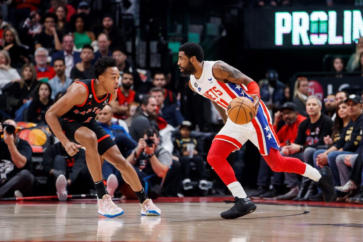 Brooklyn Nets guard Kyrie Irving (11) dribbles against Toronto Raptors forward Scottie Barnes (L), during the first half of an NBA basketball game in Toronto, on Dec. 16, 2022. (Cole Burston/The Canadian Press via AP)