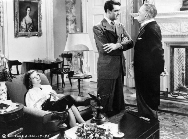 (L–R) Linda Seton (Katharine Hepburn) looks on as Johnny Case (Cary Grant) is “interviewed” by Seton family patriarch Edward Seton (Henry Kolker), in “Holiday.” (Columbia Pictures)