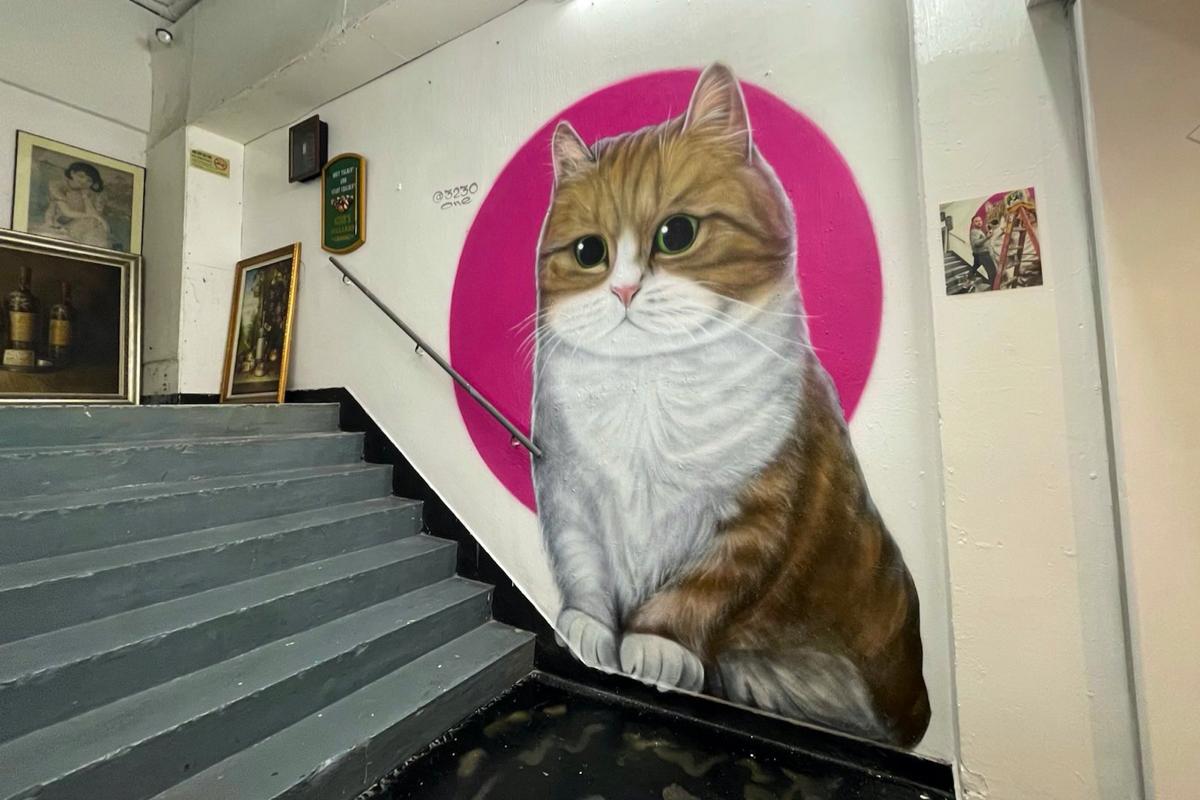 "Kwun Tong Cat" situated next to the stairs outside a restaurant painted by Vladi in How Ming Street, Kwun Tong in Hong Kong on Dec. 14, 2022. (Cheuk Sheung-yu/The Epoch Times)