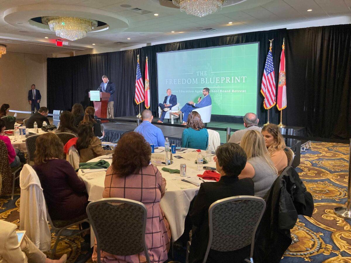 Former Florida education commissioner Richard Corcoran, seated onstage at left, and current Education Commissioner Manny Diaz, seated onstage at right, await Gov. Ron DeSantis's speech at a program Dec. 19, 2022, in Orlando. (John Haughey/The Epoch Times)
