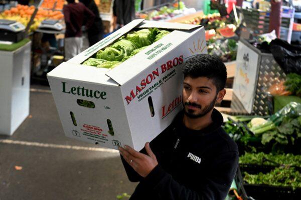 A worker holds a box of iceberg lettuce at Queen Victoria Market in Melbourne, Australia, on June 7, 2022. (William West/AFP via Getty Images)