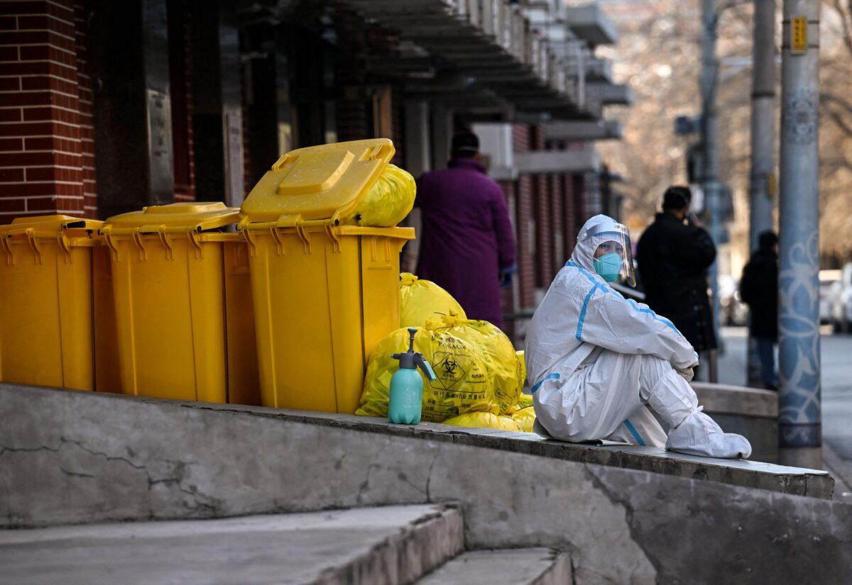 A worker wearing personal protective equipment (PPE) sits next to waste material outside a fever clinic amid the COVID-19 pandemic in Beijing on Dec. 19, 2022. (Noel Celis/AFP via Getty Images)
