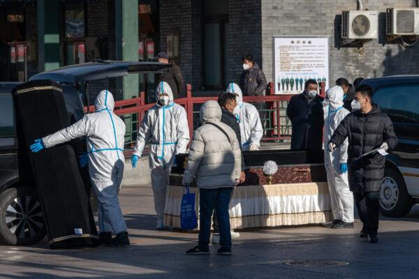 Workers in protective gear handle a coffin and coffin case at Dongjiao Funeral Parlor in Beijing on Dec. 19, 2022. (Bloomberg via Getty Images)