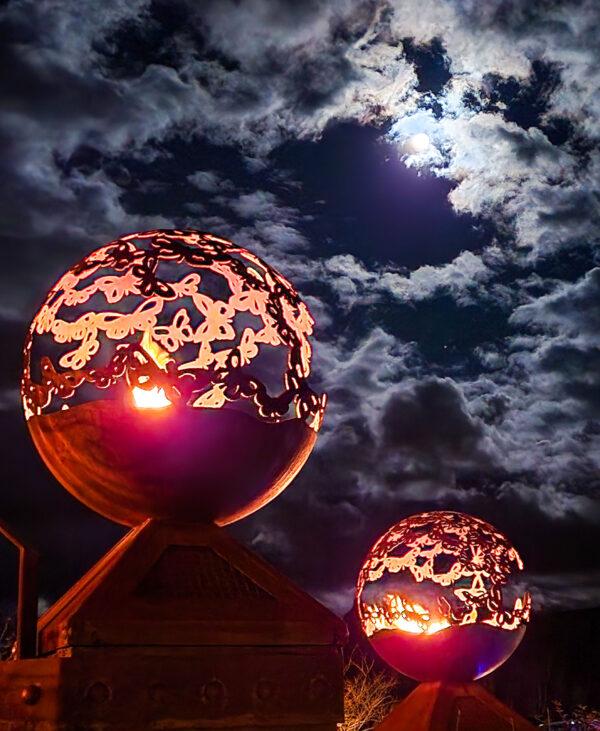 A pair of fire globes cast an eerie glow under a nearly full moon in Sedona, Ariz., on Dec. 7, 2022. (Allan Stein/The Epoch Times)
