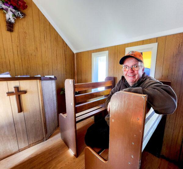 Joe Kirsh, of Pennsylvania, sits in a center pew inside Loren Pratt's Little Chapel in Yuma, Ariz., on Dec. 8, 2022. (Below) The guest book sits at the altar for visitors to sign. (Allan Stein/The Epoch Times)