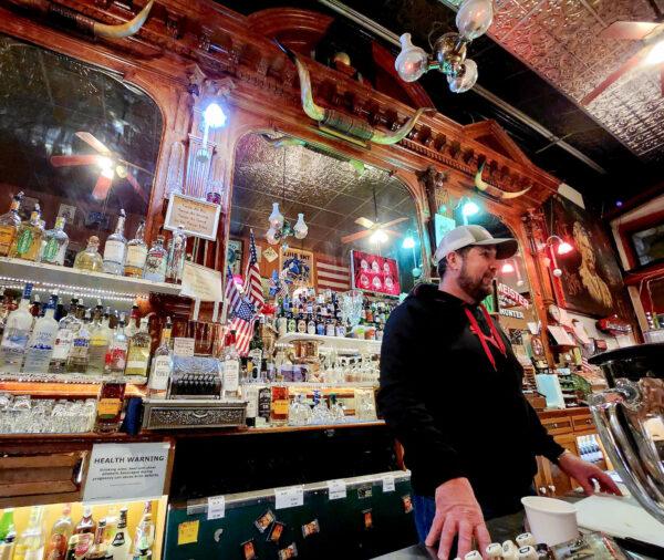 Charlie Seaton mans the bar at the Silver Queen Saloon in Virginia City, Nev., on Dec. 10, 2022. Seaton said the building once housed the newspaper that Samuel Clemens (Mark Twain) worked for during the late 1800s. (Allan Stein/The Epoch Times)