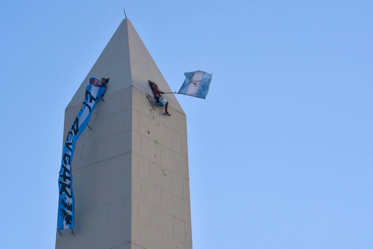 Soccer fans wave flags from the Obelisk monument as they wait to see the Argentine soccer team that won the World Cup, in Buenos Aires, Argentina, on Dec. 20, 2022. (Gustavo Garello/AP Photo)
