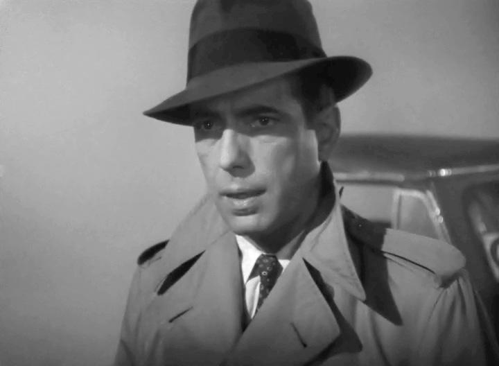 Humphrey Bogart in a trenchcoat and fedora in the airport scene of "Casablanca" (1942). (Public Domain)