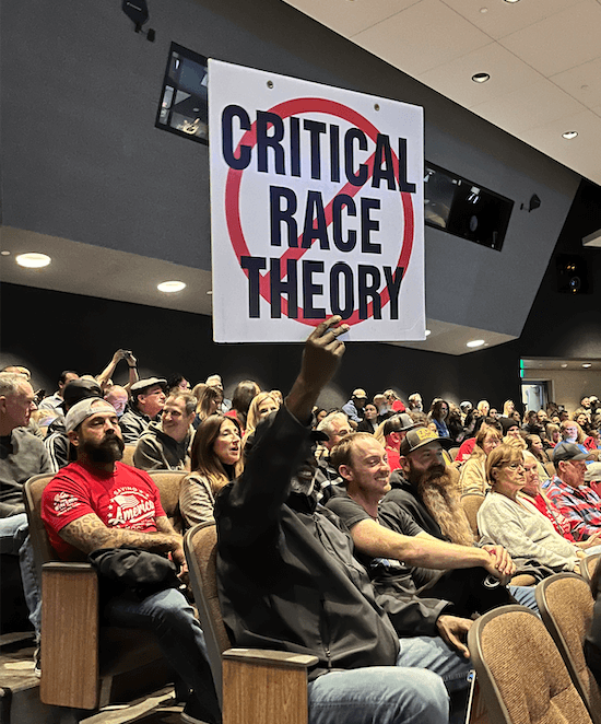 A man at a school board meeting holds up a sign protesting critical race theory on Dec. 13, 2022 in Temecula, Calif. (The Epoch Times)