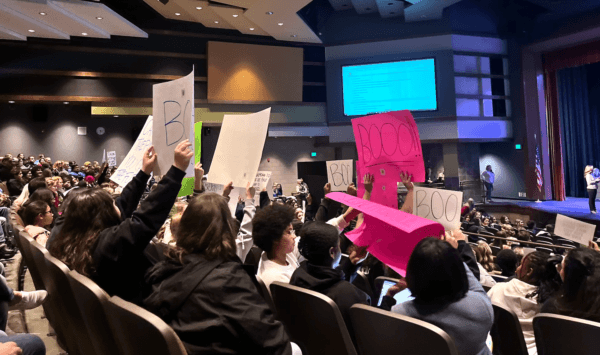 People hold up signs at a school board meeting in Temecula, Calif., on Dec. 13, 2022. (The Epoch Times)