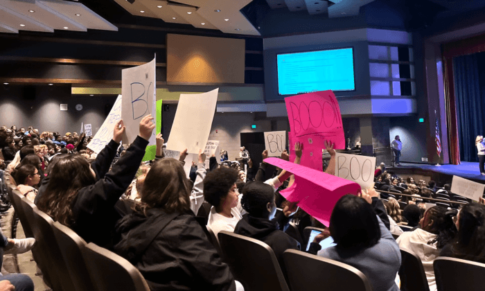 School board meeting attendees hold up signs in Temecula, Calif., on Dec. 13, 2022. (The Epoch Times)