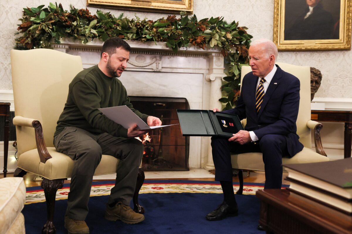 Ukraine's President Volodymyr Zelenskyy delivers a soldier's gift to U.S. President Joe Biden in the Oval Office at the White House on Dec. 21, 2022. (Leah Millis/Reuters)