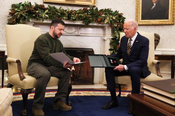 Ukraine's President Volodymyr Zelenskyy (L) delivers a soldier's gift to U.S. President Joe Biden in the Oval Office at the White House on Dec. 21, 2022. (Leah Millis/Reuters)