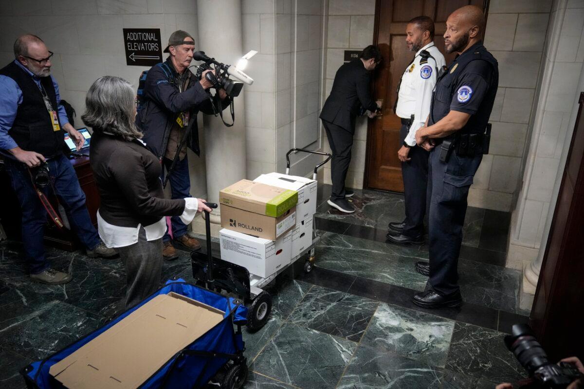 Escorted by a Capitol Police officer, staff members move boxes of documents from the hearing room to the office of the House Ways and Means Committee following a business meeting of the committee in Washington on Dec. 20, 2022. (Drew Angerer/Getty Images)