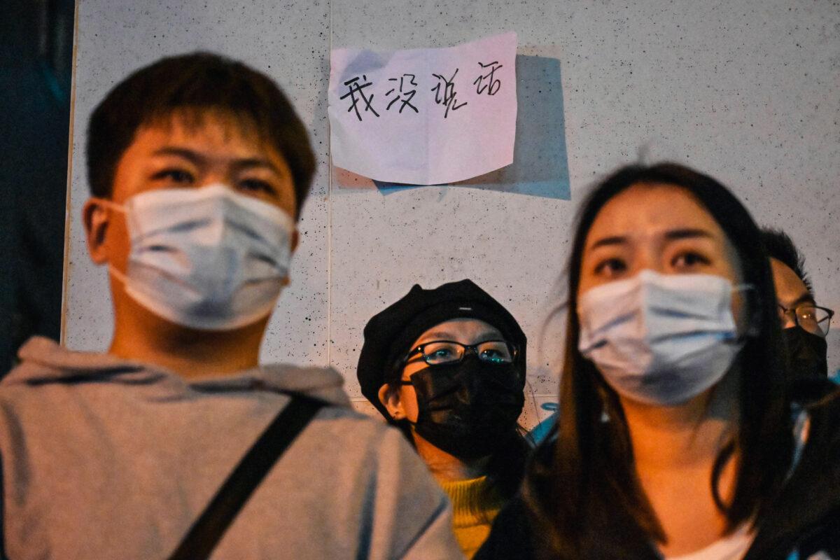 A piece of paper reads "I didn't say anything," behind protestors in Shanghai who rail against the Chinese regime's censorship while calling for an end to COVID-19 lockdowns, on Nov. 27, 2022. (HECTOR RETAMAL/AFP via Getty Images)