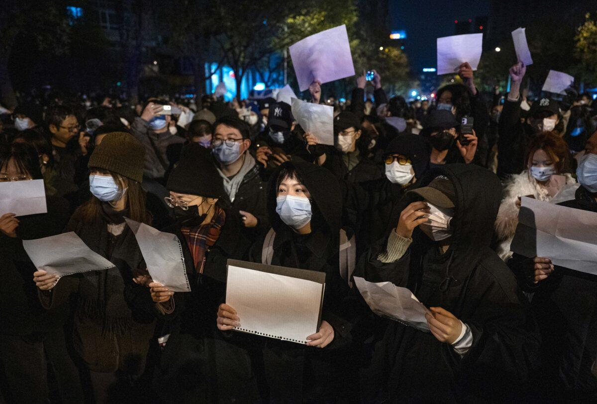Protesters hold up white paper to protest against censorship and China’s strict zero-COVID policy, in Beijing, on Nov. 27, 2022. (Kevin Frayer/Getty Images)