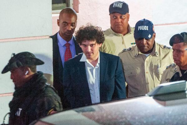 Sam Bankman-Fried, founder and former CEO of the failed cryptocurrency exchange FTX, is led away in handcuffs by officers of the Royal Bahamas Police Force in Nassau, Bahamas, on Dec. 13, 2022. (Mario Duncanson/AFP via Getty Images)