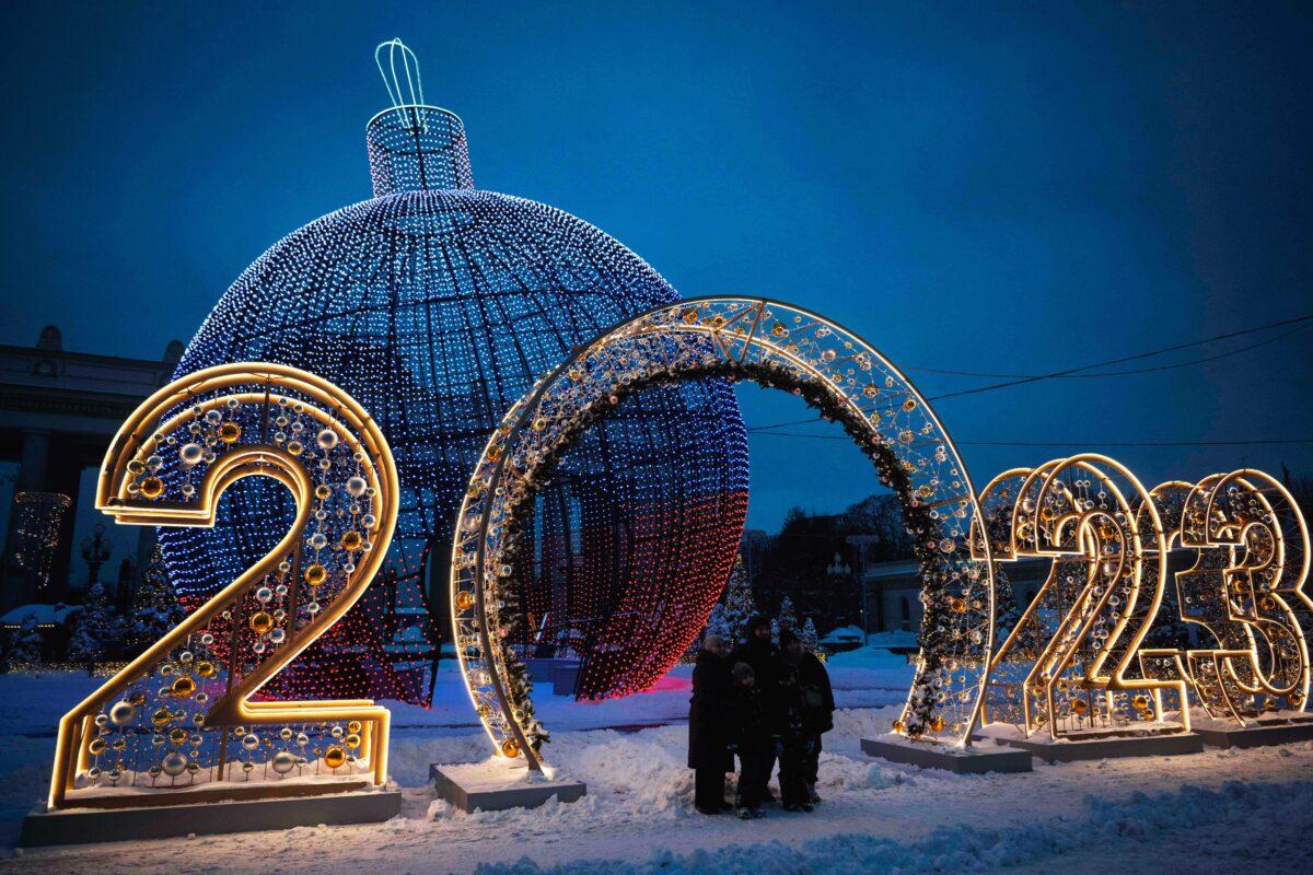 A family poses together for a photo in front of Christmas and New Year decorations in Moscow on Dec. 19, 2022. (NATALIA KOLESNIKOVA/AFP via Getty Images)
