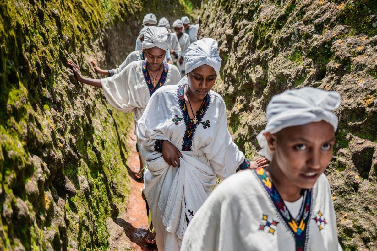 Young women walk through the cave of Saint George on Aug. 22, 2022, during the Ashenda festival, which marks the end of a two-week-long fasting period, when the faithful in the Ethiopian Orthodox Tewahedo Church gather to honor the Virgin Mary. (AMANUEL SILESHI/AFP via Getty Images)