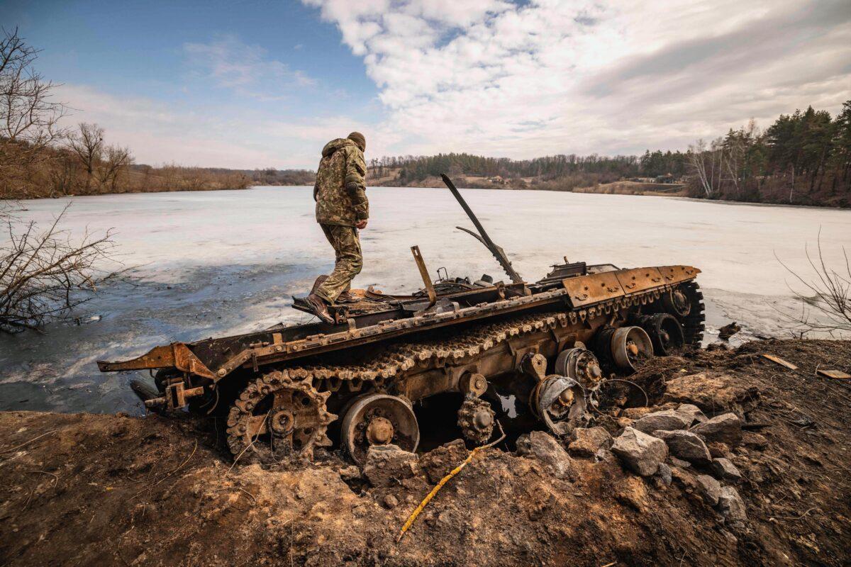 A Ukrainian serviceman stands on a destroyed Russian tank in the northeastern Ukrainian city of Trostyanets after Ukraine stated that it recaptured the town; one of the first to fall under Moscow's control, on March 29, 2022. (FADEL SENNA/AFP via Getty Images)