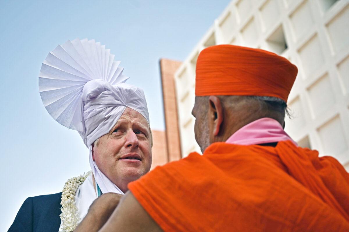 UK Prime Minister Boris Johnson gets a traditional turban tied on his head after arriving at a university in Gandhinagar during a two-day trip to India, on April 21, 2022. (Ben Stansall - WPA Pool/Getty Images)