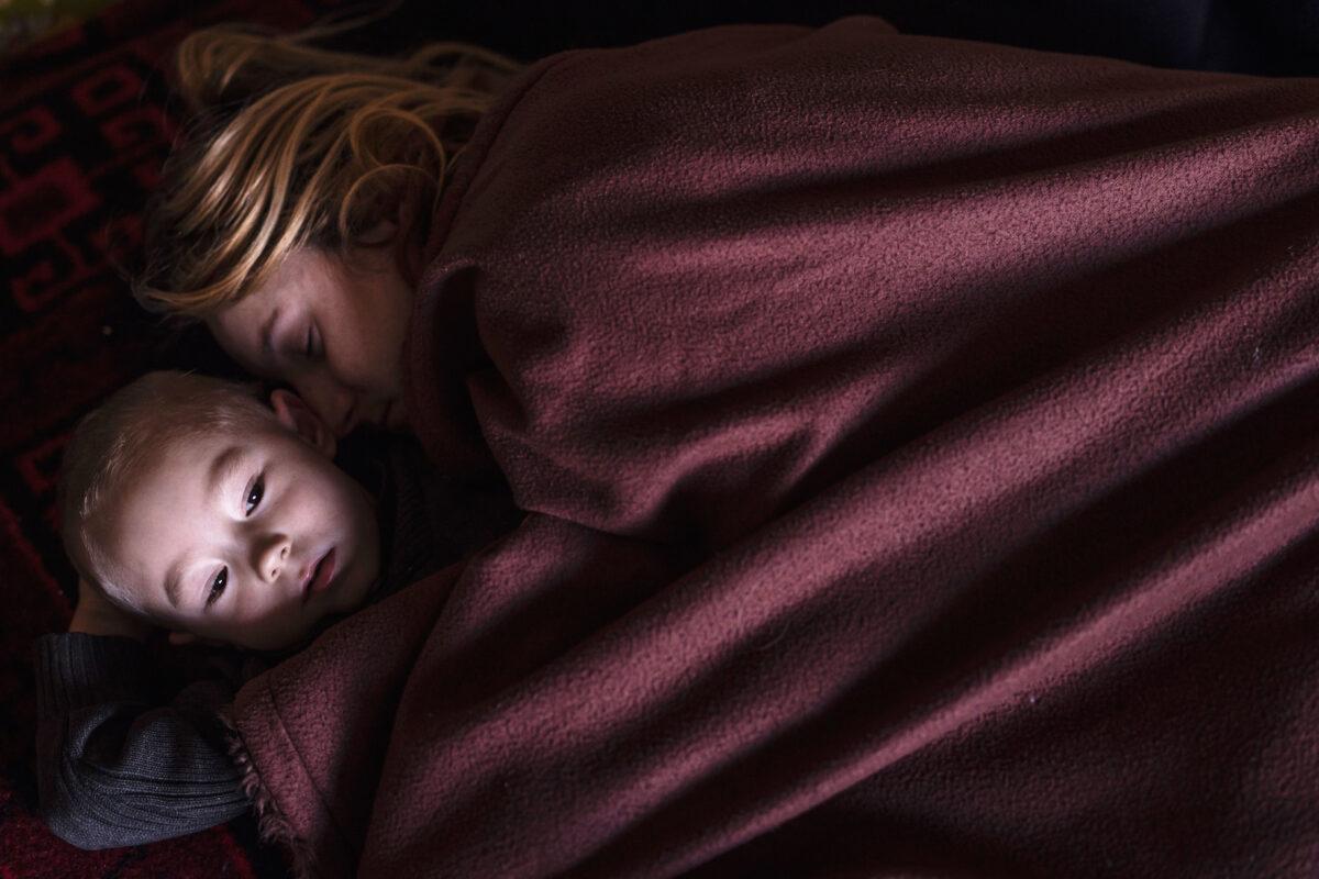 A mother and son sleep in a family area in Lviv, Ukraine, while waiting to board a train to Poland. More than 2 million people have fled Ukraine in the past three weeks, on March 12, 2022. (Dan Kitwood/Getty Images)